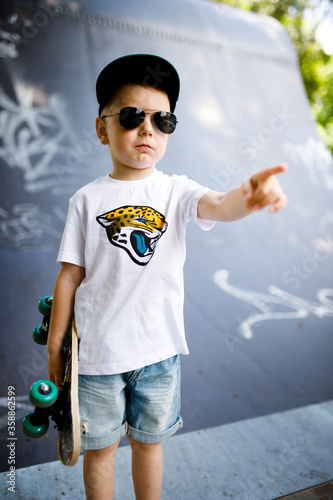 Boy with a skate in a skate park. A boy with glasses learns to skate.