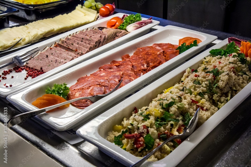 Serving bowls with delicious ham and meat and steamed vegetables with rice at buffet lunch.
