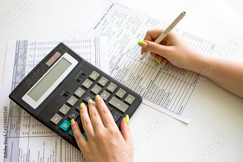 Financial data analyzing. Counting on calculator. Hand with pen on financial table