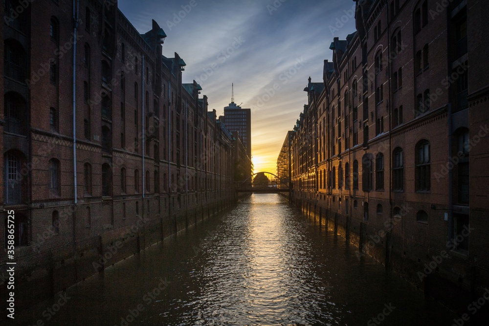 Canal in Hamburg, Germany, and pedestrian bridge across it in the evening. Sunset. The Speicherstadt, the largest warehouse district in the world. .
