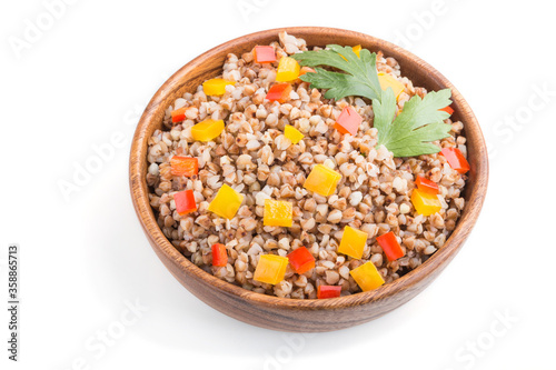 Buckwheat porridge with vegetables in wooden bowl isolated on white background. Side view, close up.