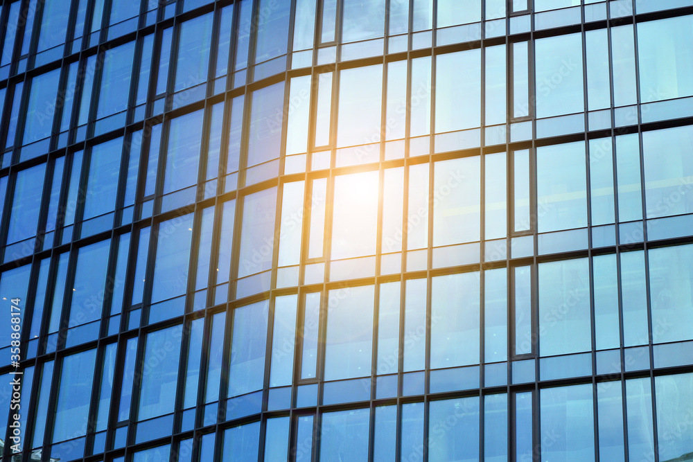 Facade texture of a glass mirrored office building. Fragment of the facade. Bottom view of modern skyscrapers in business district in evening light at sunset with lens flare filter effect. Facade texture of a glass mirrored office building. Fragment of the facade. Bottom view of modern skyscrapers in business district in evening light at sunset with lens flare filter effect.