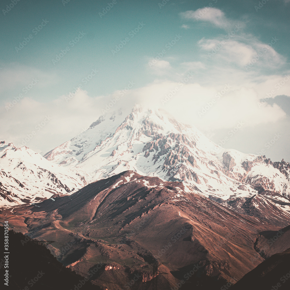 Square backgroud image of  viw to KAzbek mountain top half covered in snow during spring. Georgia mountains and caucausus rock climbing. 2020