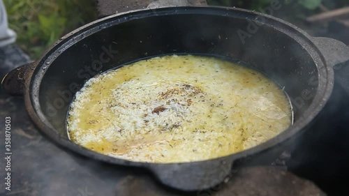 cooking Uzbek pilaf in a cauldron on fire in nature during a hike, national food, hiking food, nobody photo