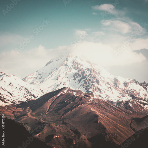 Square backgroud image of viw to KAzbek mountain top half covered in snow during spring. Georgia mountains and caucausus rock climbing. 2020