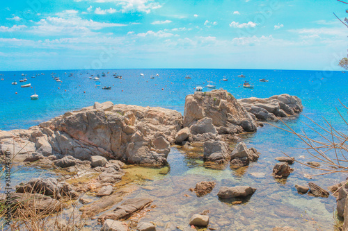 Rocky coast in the Mediterranean with fishing boats in the background