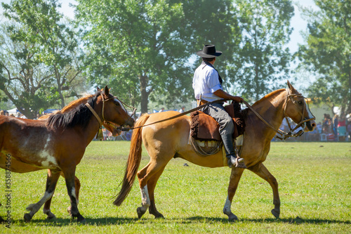 Gaucho riding a horse while transporting a second animal on the day of the tradition in San Antonio de Areco, Argentina.