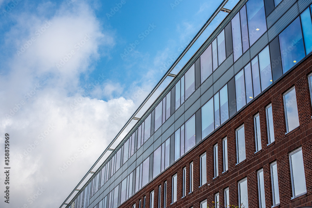 Facade of an office building with blue, cloudy skies in the background Facade of an office building with blue, cloudy skies in the background
