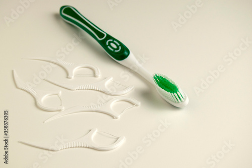 the green toothbrush is on a white background. Nearby are dental flosses.