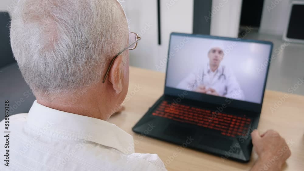 Senior man having videoconferencing with online male doctor. Remote patient consulting video call in conference virtual webcam chat app. Over shoulder laptop screen view.