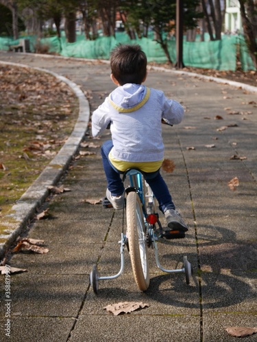An infant boy practising riding a bicycle