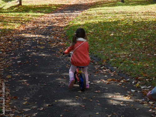 An infant girl practising riding a bicycle