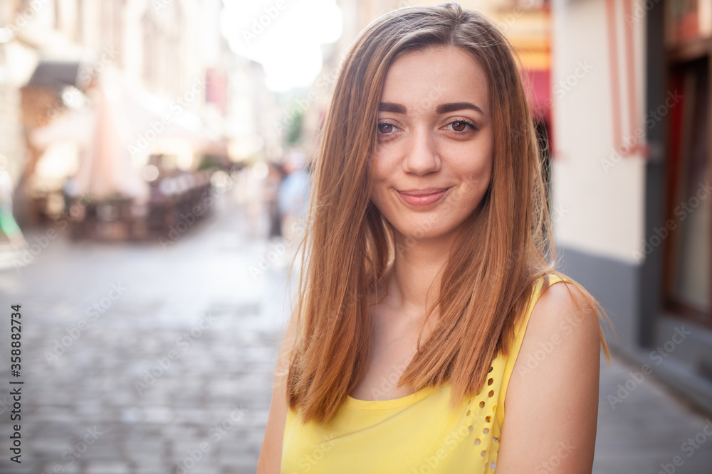 Beautiful young woman in urban scenery, downtown, smiling at camera