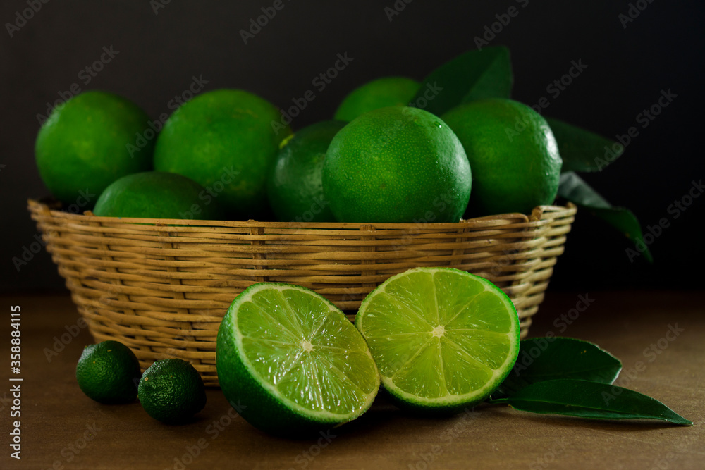 Closeup of some green lemons in a basket on a wooden surface Closeup of some green lemons in a basket on a wooden surface