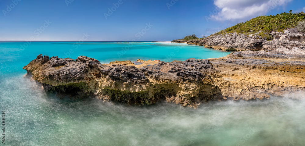 Beautiful panoramic view of a cliff in tropics. Turquoise water. Blue sky as a background. Long exposure.