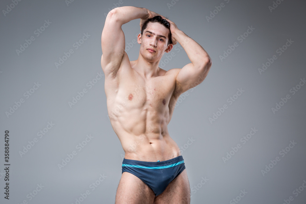 Studio portrait young Caucasian man on gray background posing. theme of puberty, problem skin, teen acne. Caucasian athlete fitness. Allergy sports nutrition, supplements steroids
