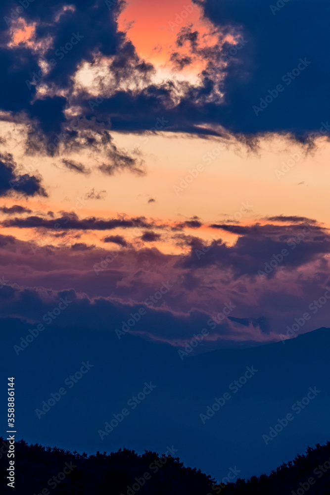 nubi al tramonto 01 - sopra le montagne iln lontananza nubi scure si accumulano in un cielo al tramonto dai colori intensi
