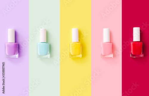 Group of nail polishes of different colors on colorful background. Top view