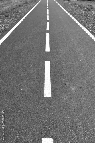 Perspective road marked with white dotted lines. grass along the way. black and white image.