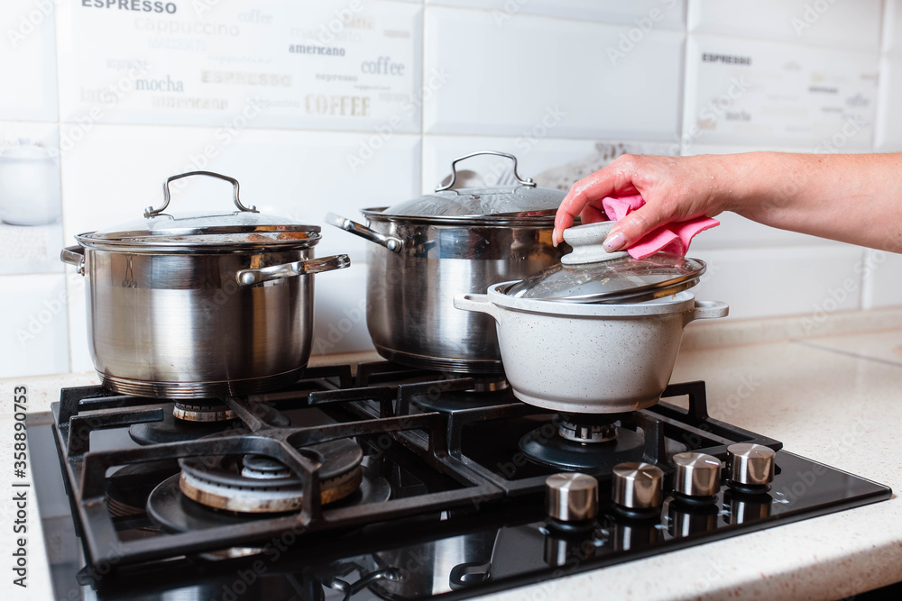Utensils for cooking classes on stove in kitchen. Metal pans on kitchen counter. Female chef cooking in restaurant kitchen. Utensils for cooking classes on stove in kitchen. Metal pans on kitchen counter. Female chef cooking in restaurant kitchen.