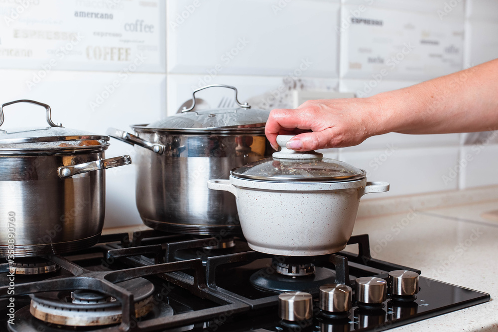 Utensils for cooking classes on stove in kitchen. Metal pans on kitchen counter. Female chef cooking in restaurant kitchen. Utensils for cooking classes on stove in kitchen. Metal pans on kitchen counter. Female chef cooking in restaurant kitchen.