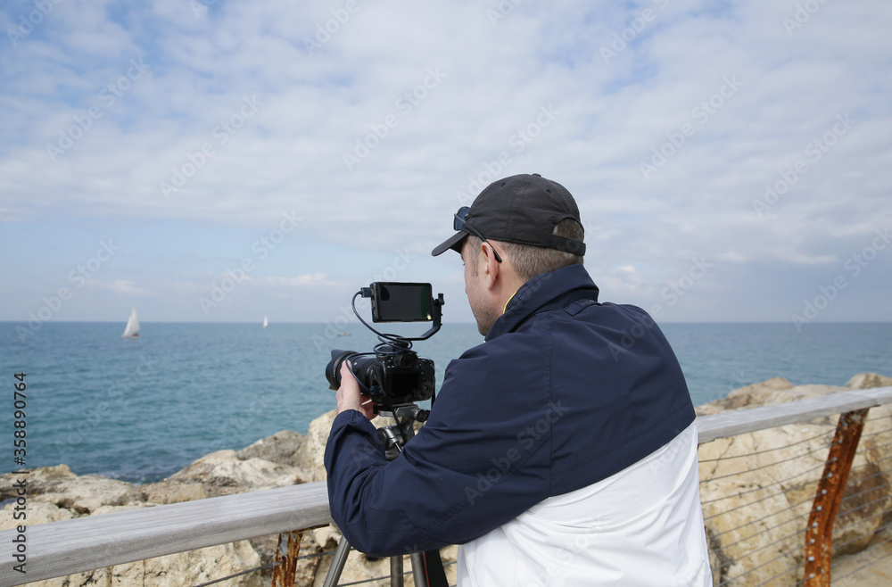 Obraz premium photographer or videographer or blogger with digital camera in action on a sea