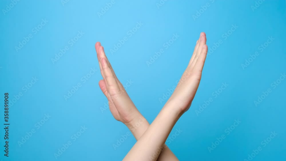 Protest sign. Close up of unrecognizable young woman crossed hands, isolated on blue studio background with copy space for advertisement. Stop signal. Advertising area, mock up. Protest sign. Close up of unrecognizable young woman crossed hands, isolated on blue studio background with copy space for advertisement. Stop signal. Advertising area, mock up.