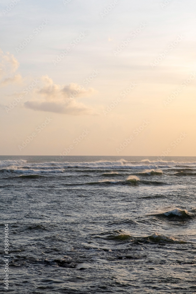 Many waves on the surface of the sea in windy weather at sunset.  Stormy sea and sunset sky