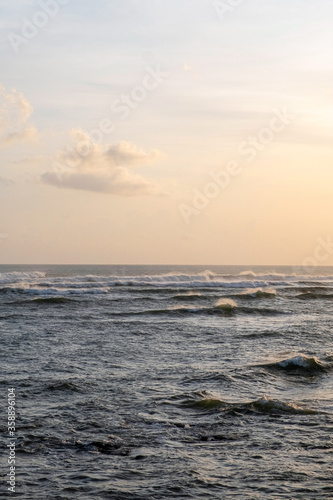 Many waves on the surface of the sea in windy weather at sunset. Stormy sea and sunset sky