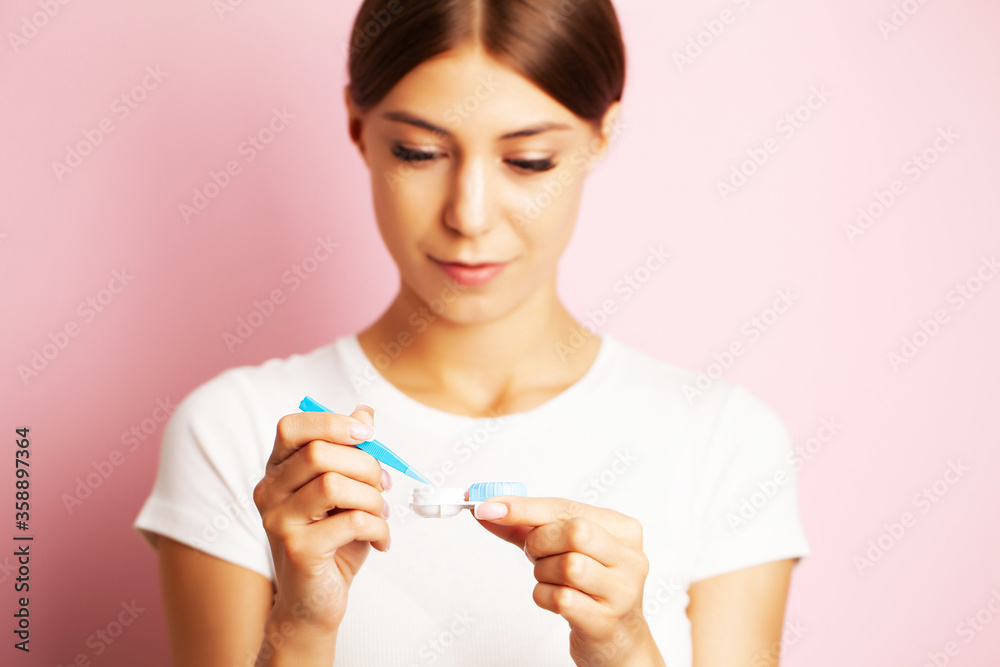 The ophthalmologist holds a container with contact lenses near the eyes The ophthalmologist holds a container with contact lenses near the eyes