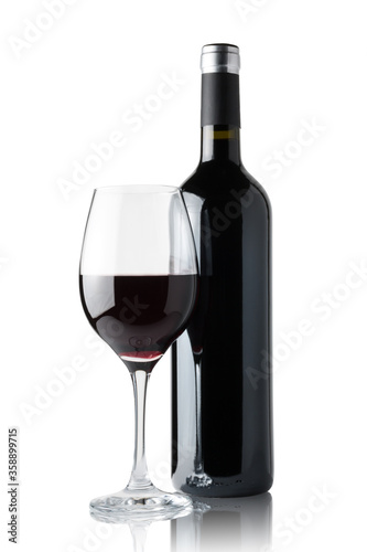 Glass of red wine next to a bottle isolated on white background