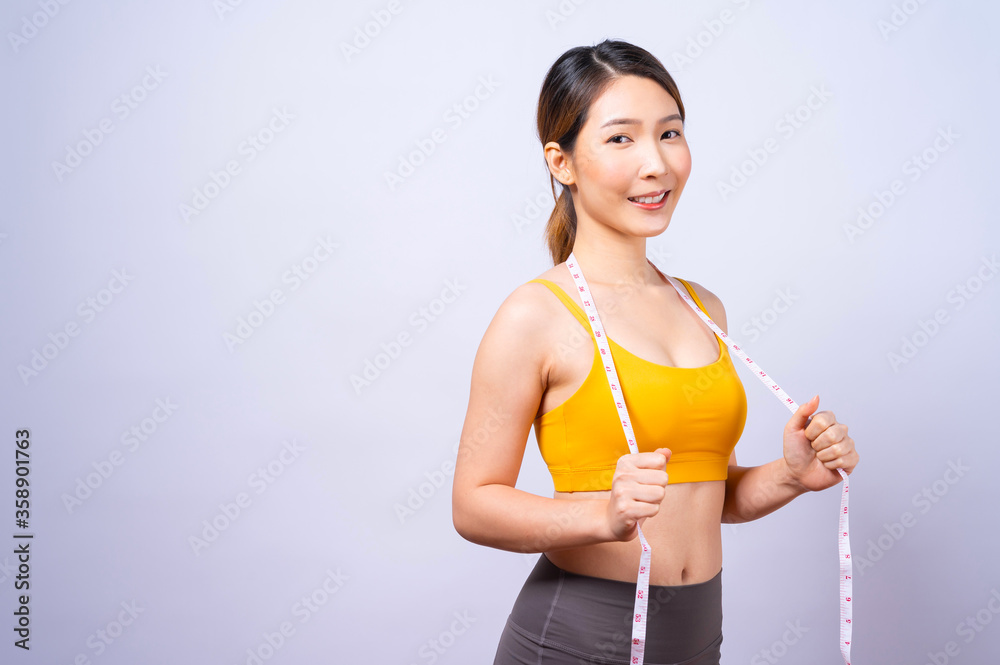 Asian sporty woman measuring her waist by measure tape isolated on white background Concept of healthy lifestyle Asian sporty woman measuring her waist by measure tape isolated on white background Concept of healthy lifestyle
