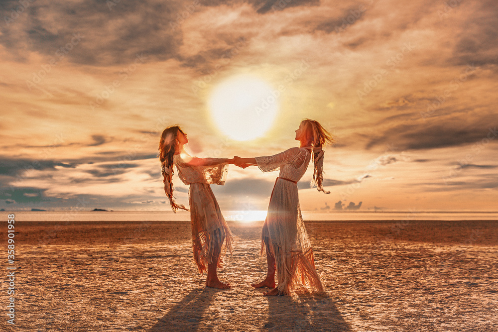 two beautiful girls having fun at sunset on the beach - obrazy, fototapety, plakaty 