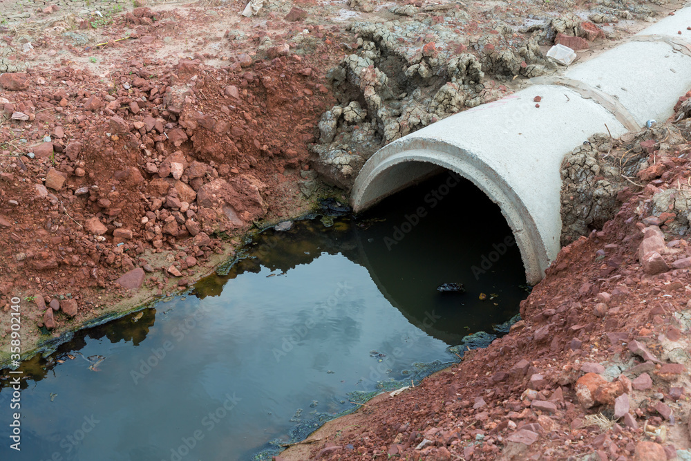 Concrete circular run-off pipe discharging water. sewage pipe polluting ...