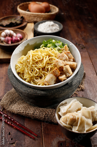 Chicken noodles and boiled dumplings. A bowl of boiled noodles is given a spice of broth and a sprinkling of pieces of chicken and leeks and celery. Isolated from Asian food.