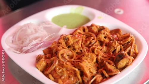 Making masala soya chaap tikka with onions and green mint chutney, served on a white plate.