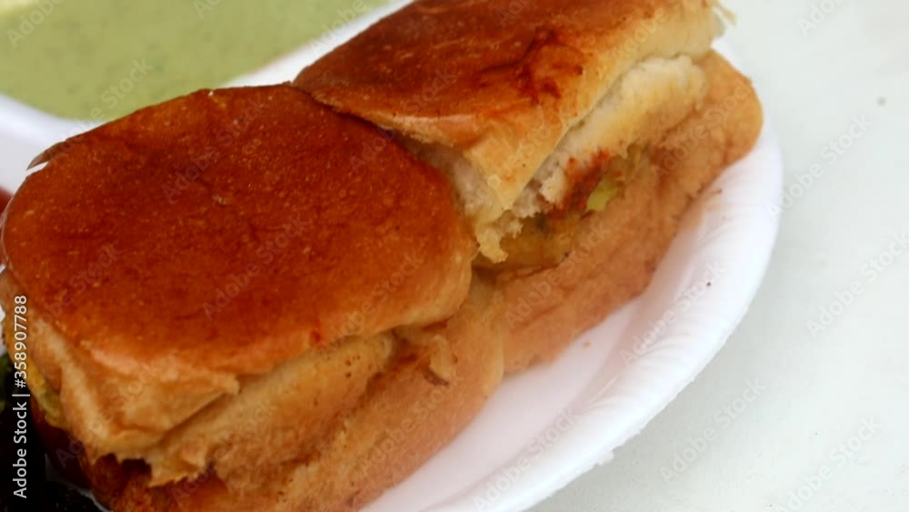 Making indian street vada pav on a fry pan served with green chutney, red tomato sauce and masala. Making indian street vada pav on a fry pan served with green chutney, red tomato sauce and masala.