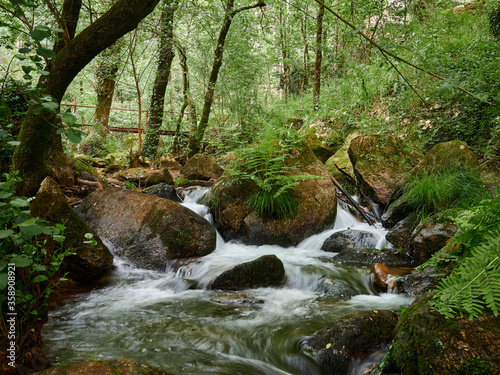 River Leça Waterfalls in Monte Cordova, Portugal. The river water runs down the big rocks of the mountain, under the green canopy of the trees in the spring