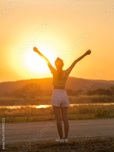 Beauty Girl Outdoors enjoying nature, raising hands. Beautiful Teenage Model girl with long healthy blowing hair running on the Spring Field, Sun Light Glow Sun. Free Happy Woman. Toned in warm colors