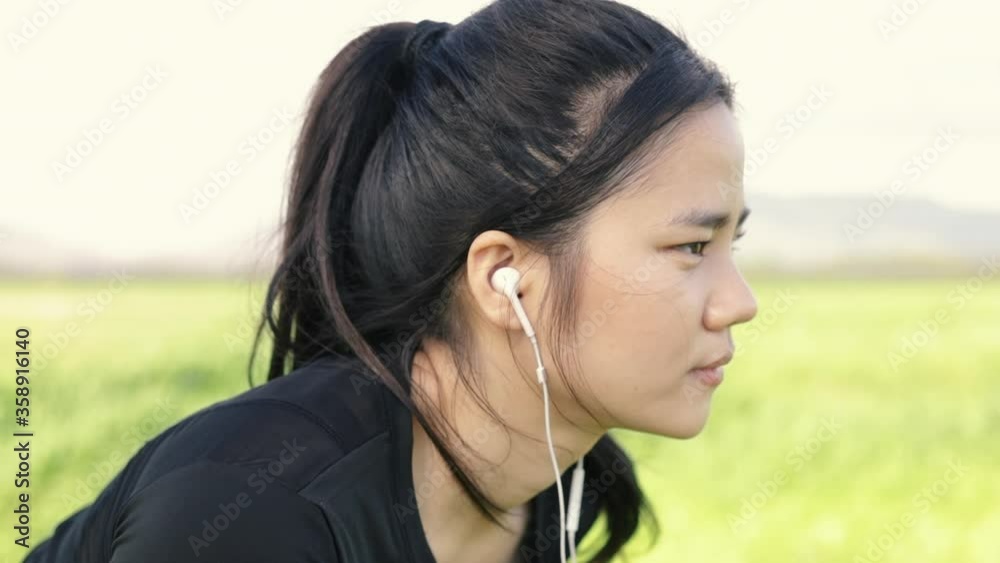 Close up portrait of young athletic asian girl relaxed enjoying peaceful sunset and looking up exhaling fresh air relaxing at a public park on the beautiful summer sunset. Close up portrait of young athletic asian girl relaxed enjoying peaceful sunset and looking up exhaling fresh air relaxing at a public park on the beautiful summer sunset.