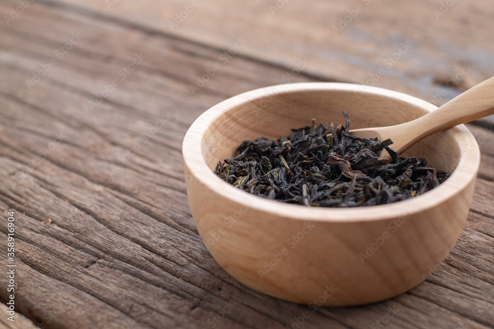 Chinese leaf tea in a wood bowl on grained wood background Chinese leaf tea in a wood bowl on grained wood background
