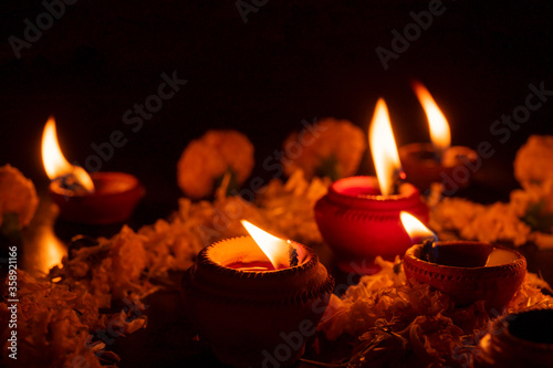 Very low angle view of Rangoli flowers and candles or diyas, Deepawali lights at night. Dark background stock image. photo