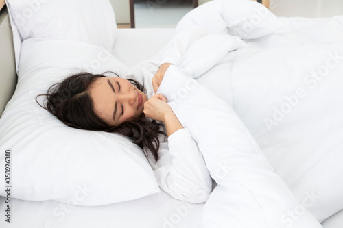 Young woman sleeping on a white bed. Beautiful Asian young woman sleep on the bed. Portrait of beautiful young sexy asian woman with attractive smile enjoy fresh soft white bed in the morning.