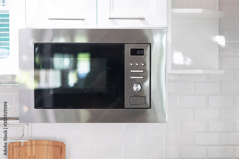 Obraz premium Microwave oven float and hanging under the cabinet on the wall in the kitchen. Interior design of cooking area for compact space in home and apartment.