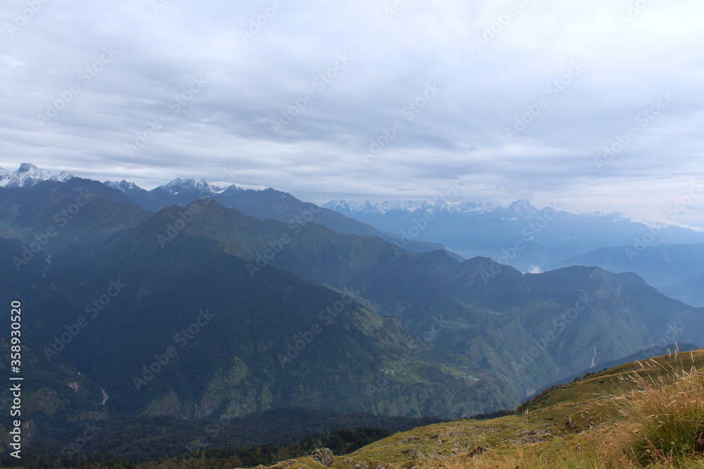 a landscape view of valley and the snow peaked mountains of lower Himalayan range.