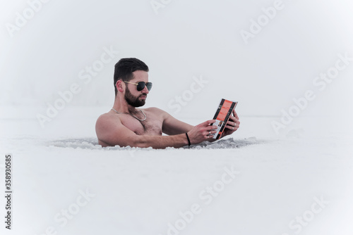 bearded young man reading a book on a frozen lake © Amir Bajric