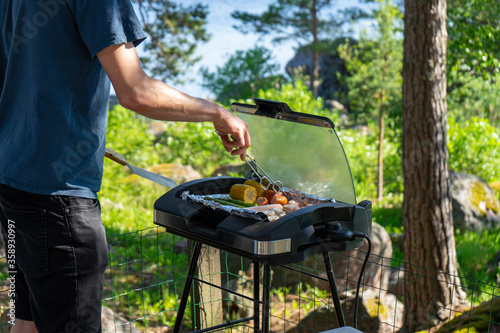 Obraz na płótnie Man preparing food and barbecue on summer day with electric grill
