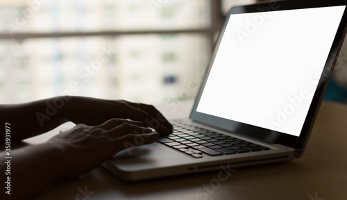 A woman's hand printed on a laptop with a white screen on her desk at home