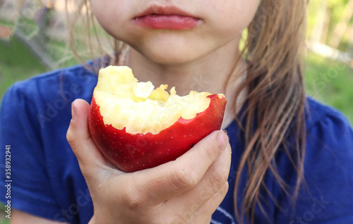 A child eats a delicious juicy Apple on the street  holding it in his hand  close-up