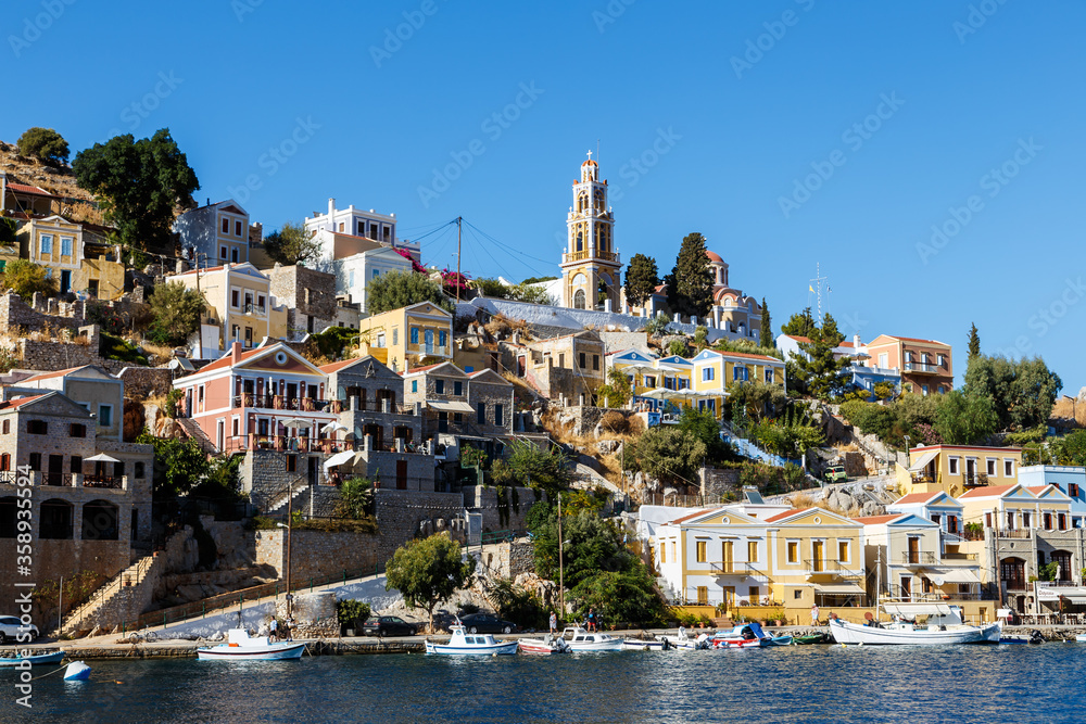 Fototapeta premium Greece. Dodecanesse. Island Symi. Colorful houses on rocks. Italian architecture, doll houses on the slopes of rocky coast